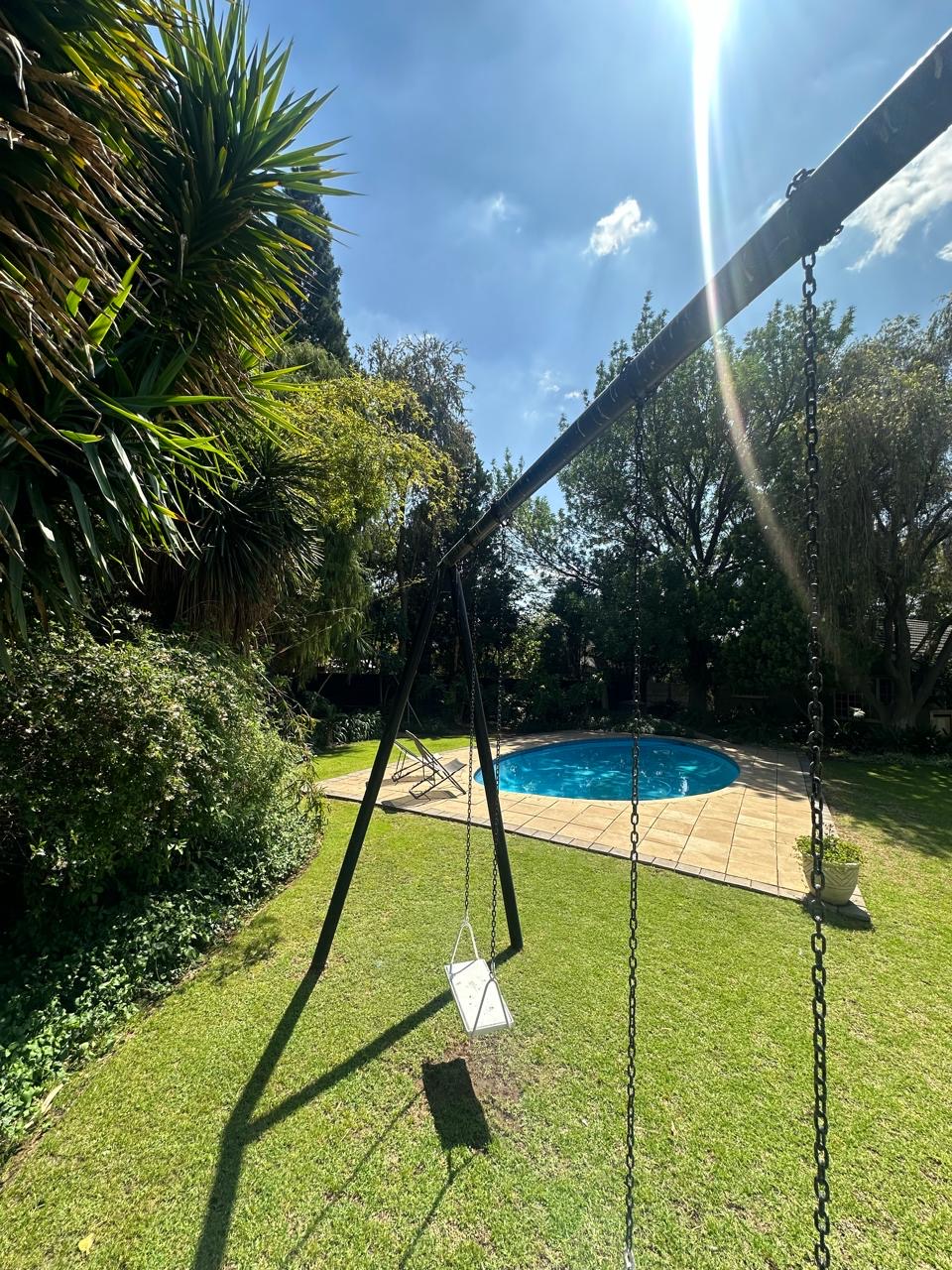 Lush garden and pool view with swing at Cherry Nest
