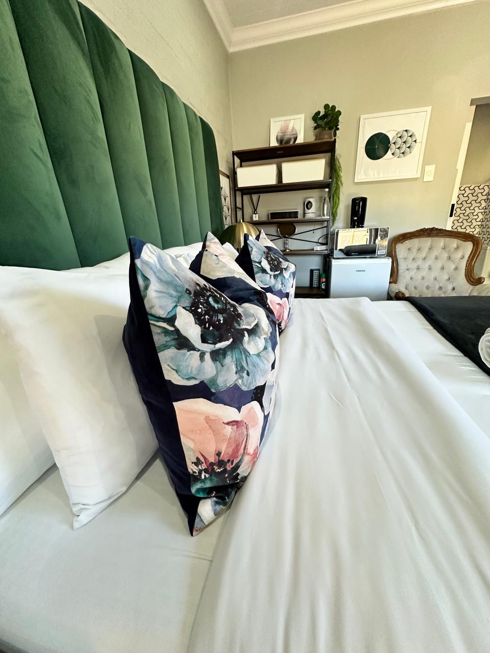 Room 10 dressed bed with floral cushions and green headboard