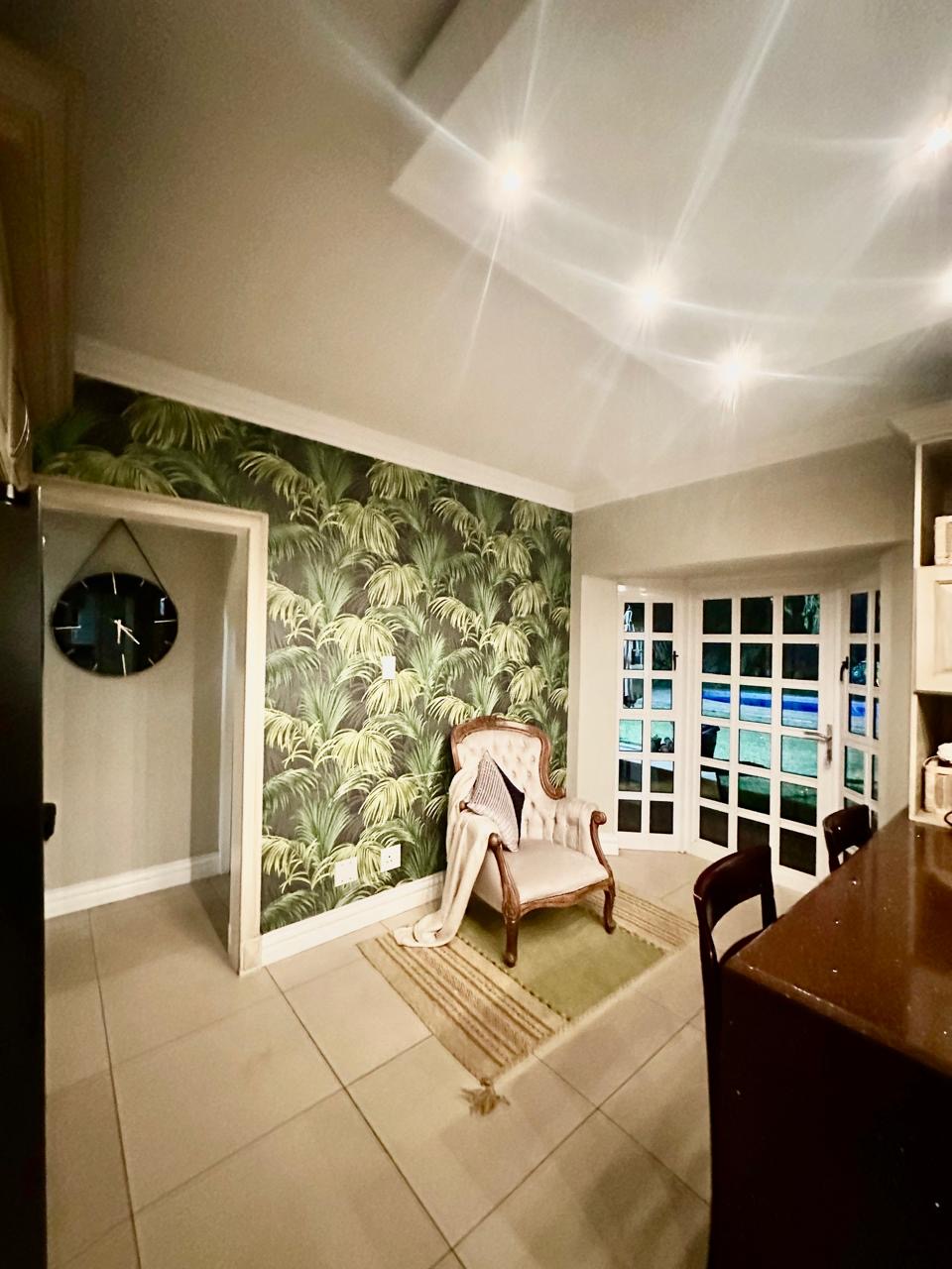 Dining corner with palm wallpaper and French doors at Cherry Nest