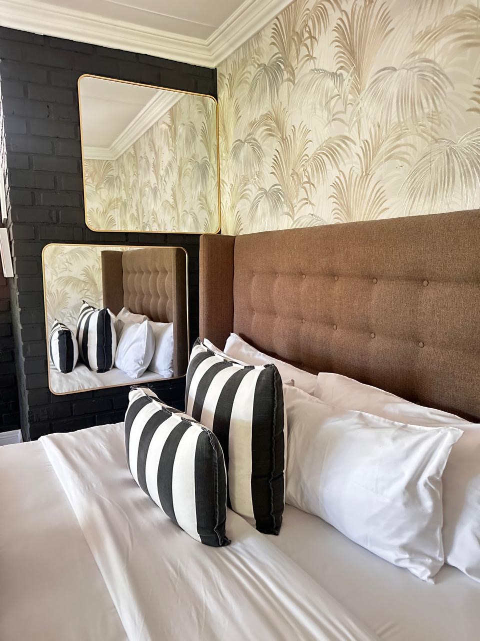 Room 1 king bed with upholstered headboard and striped cushions