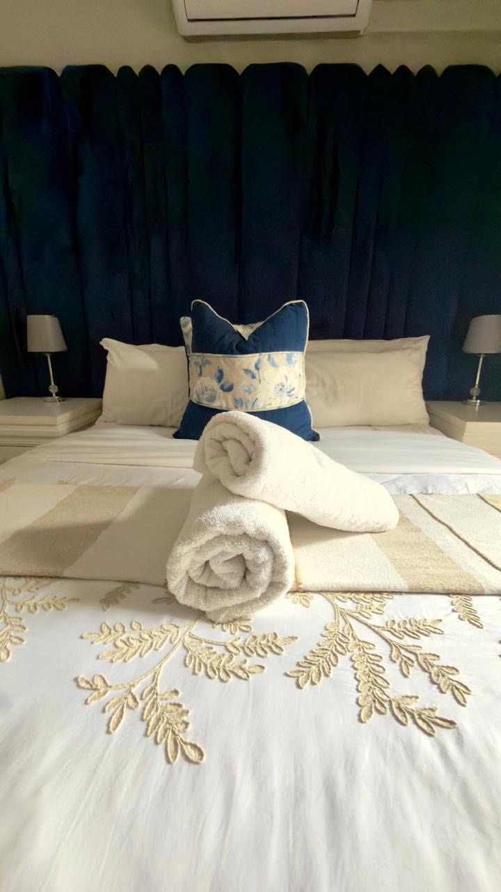 Room 8 queen bed with blue velvet headboard and dressed white bedding