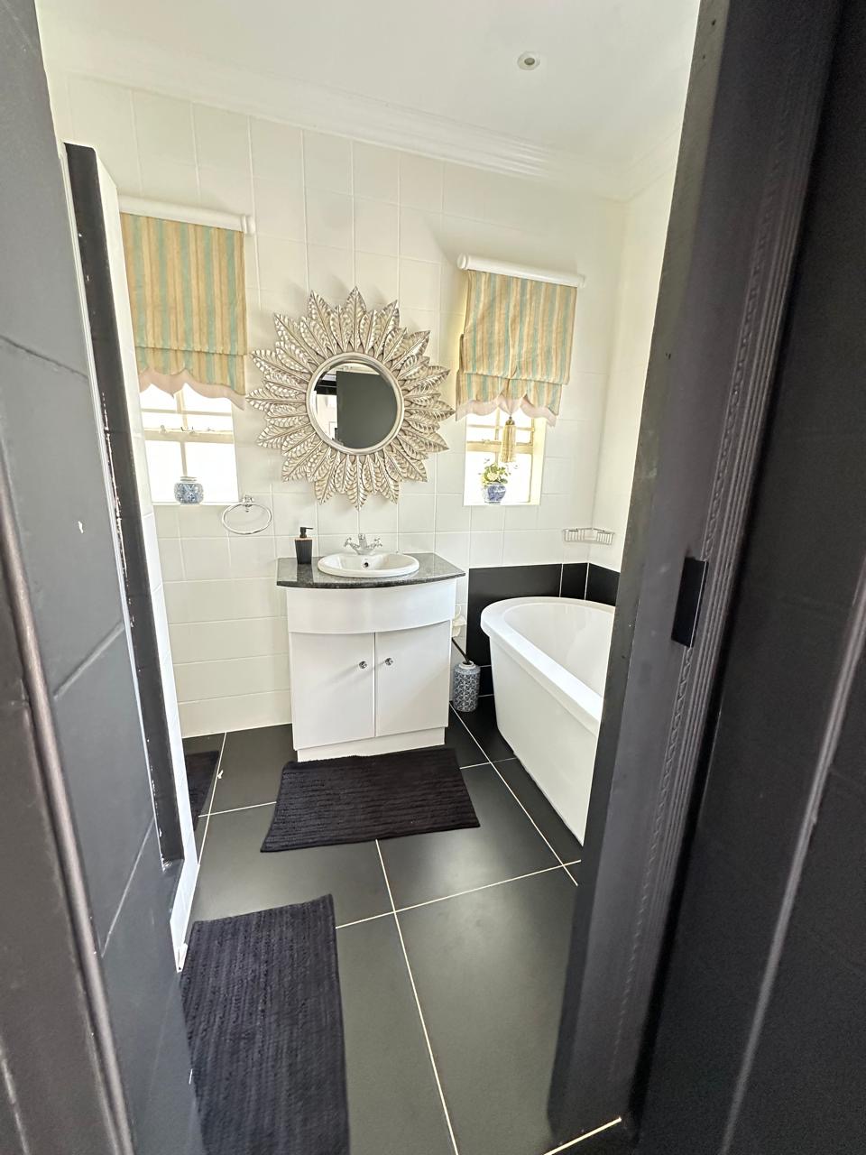 Room 2 en-suite bathroom with sunburst mirror and bath