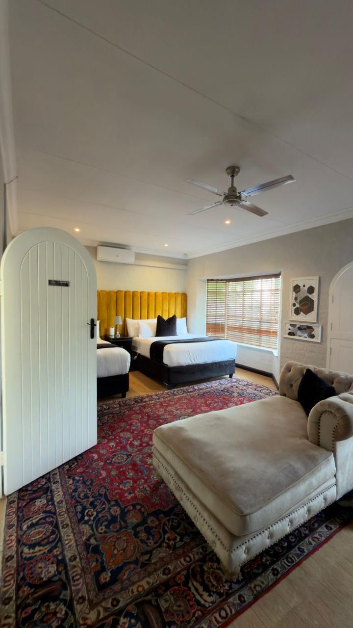 Room 9 with two queen beds, yellow headboard and Persian rug